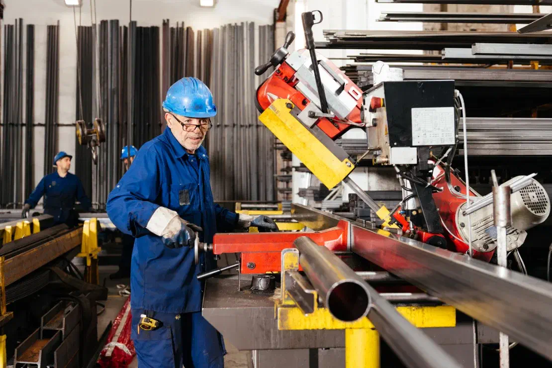 A production operative cutting a steel tube to length in a fabrication workshop