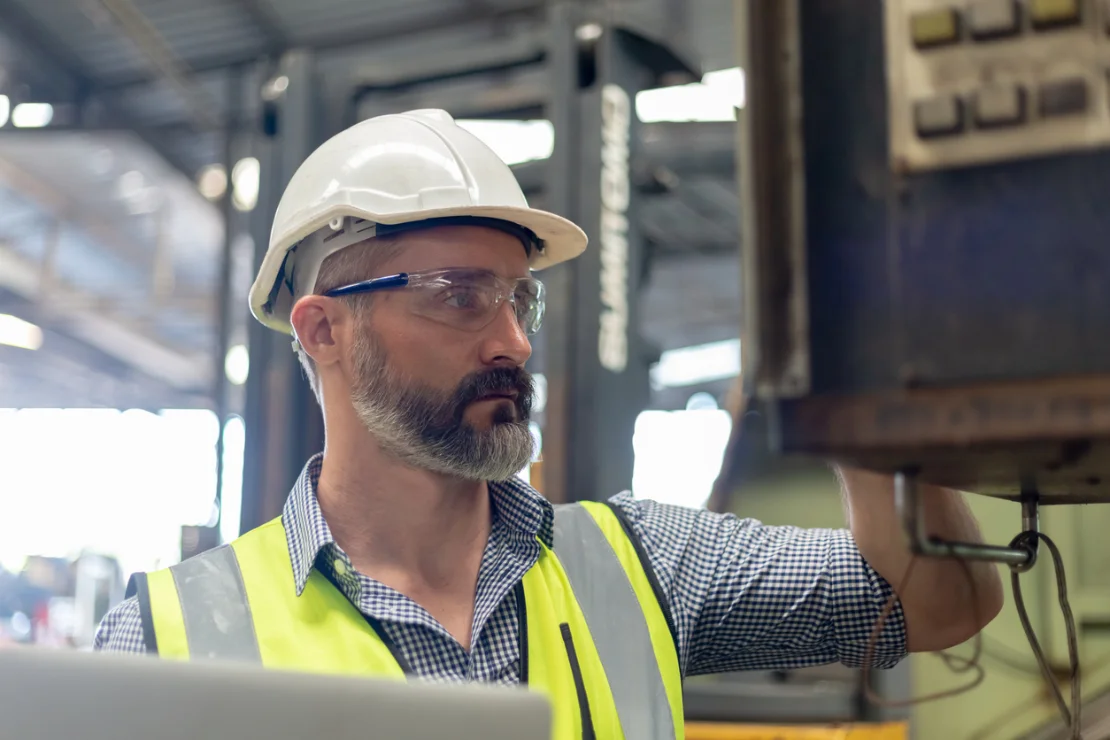 Male employee reviewing compliance documents in an industrial setting